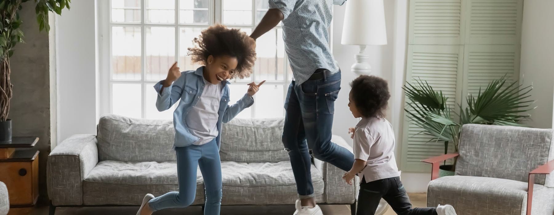 father dancing around the living room with his two kids